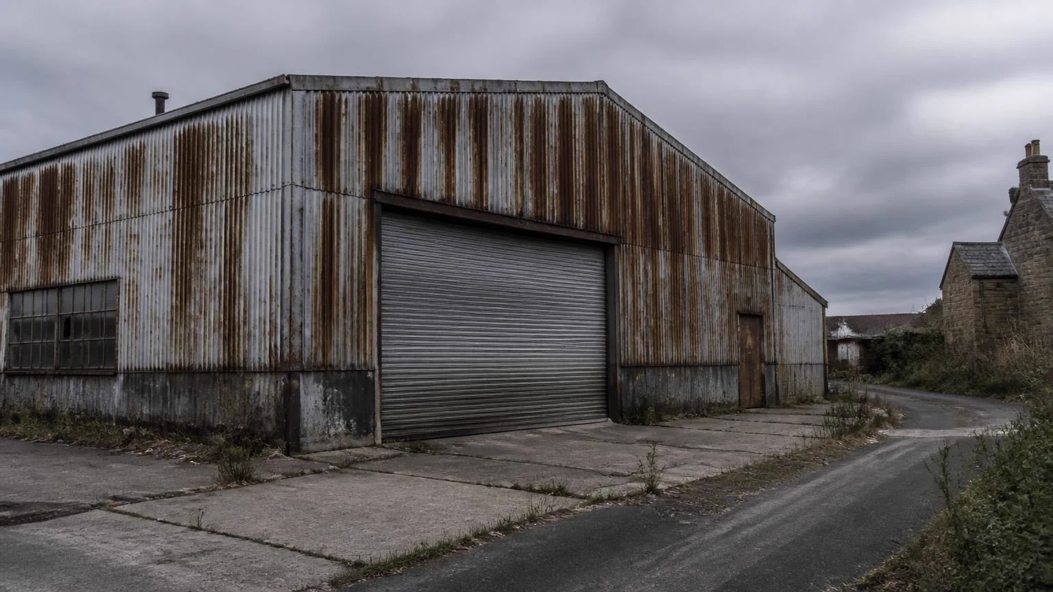 A tired industrial shed with corrugated cladding and a roller shutter door